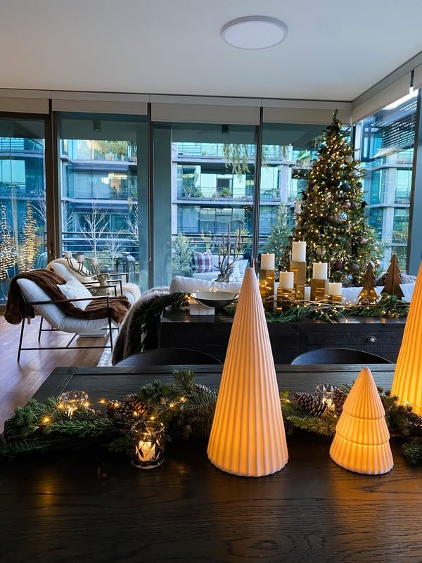 A modern apartment living room dressed with a tree, garland and glowing cone lamps