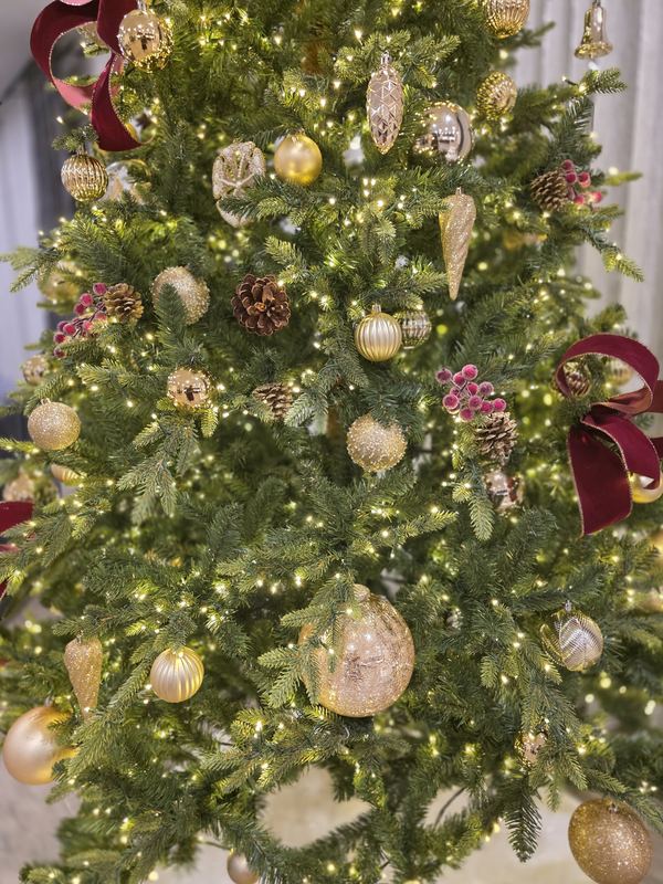 Close detail of ornaments and burgundy ribbon on a residence tree